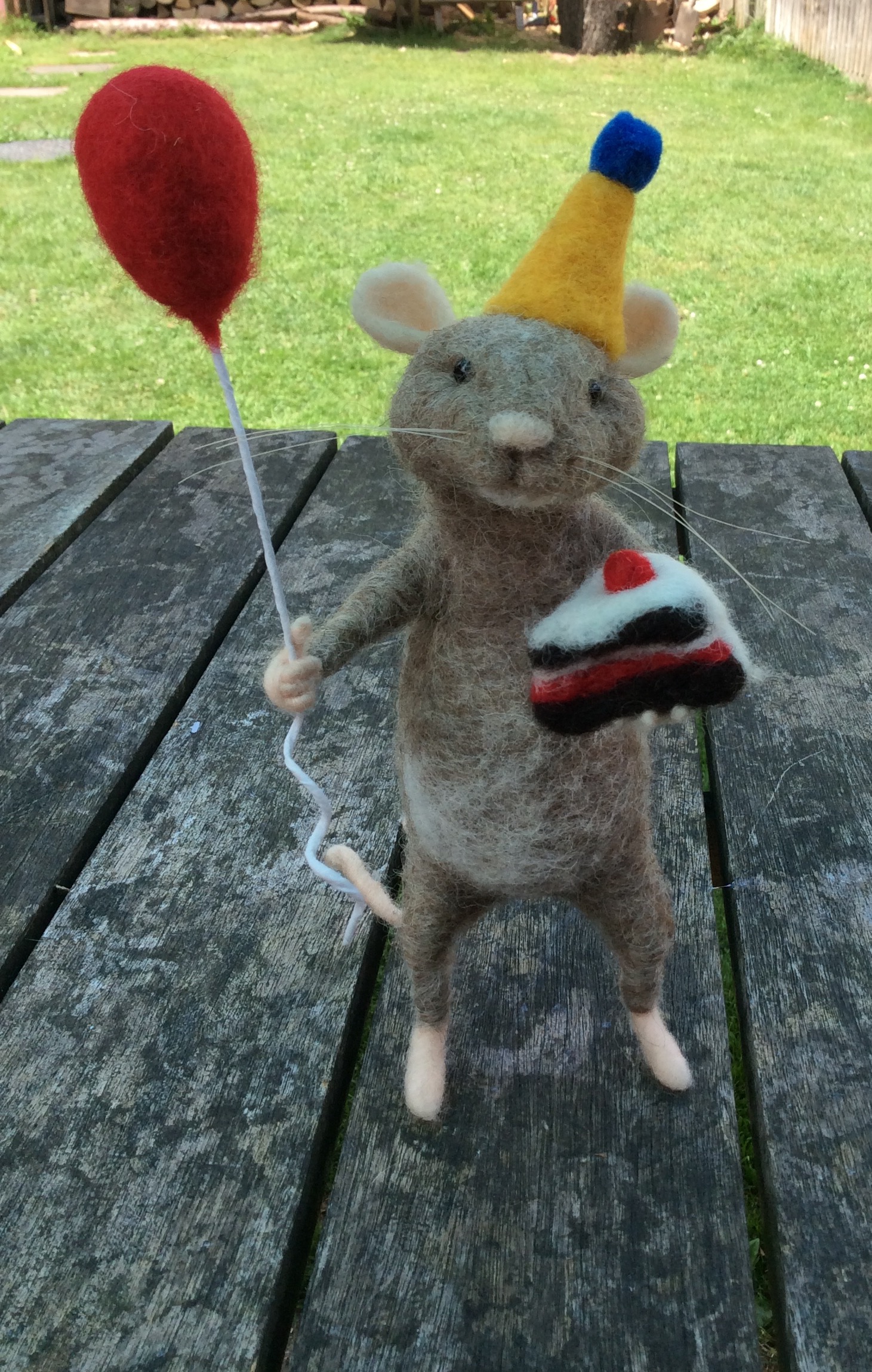 Felt mouse holding cake and balloon.