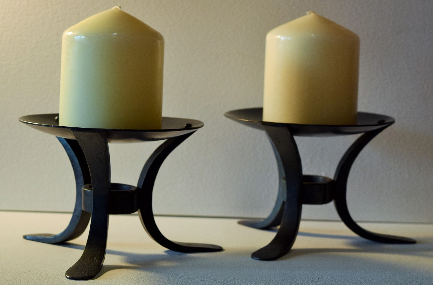 Two black candle holders with white candles.