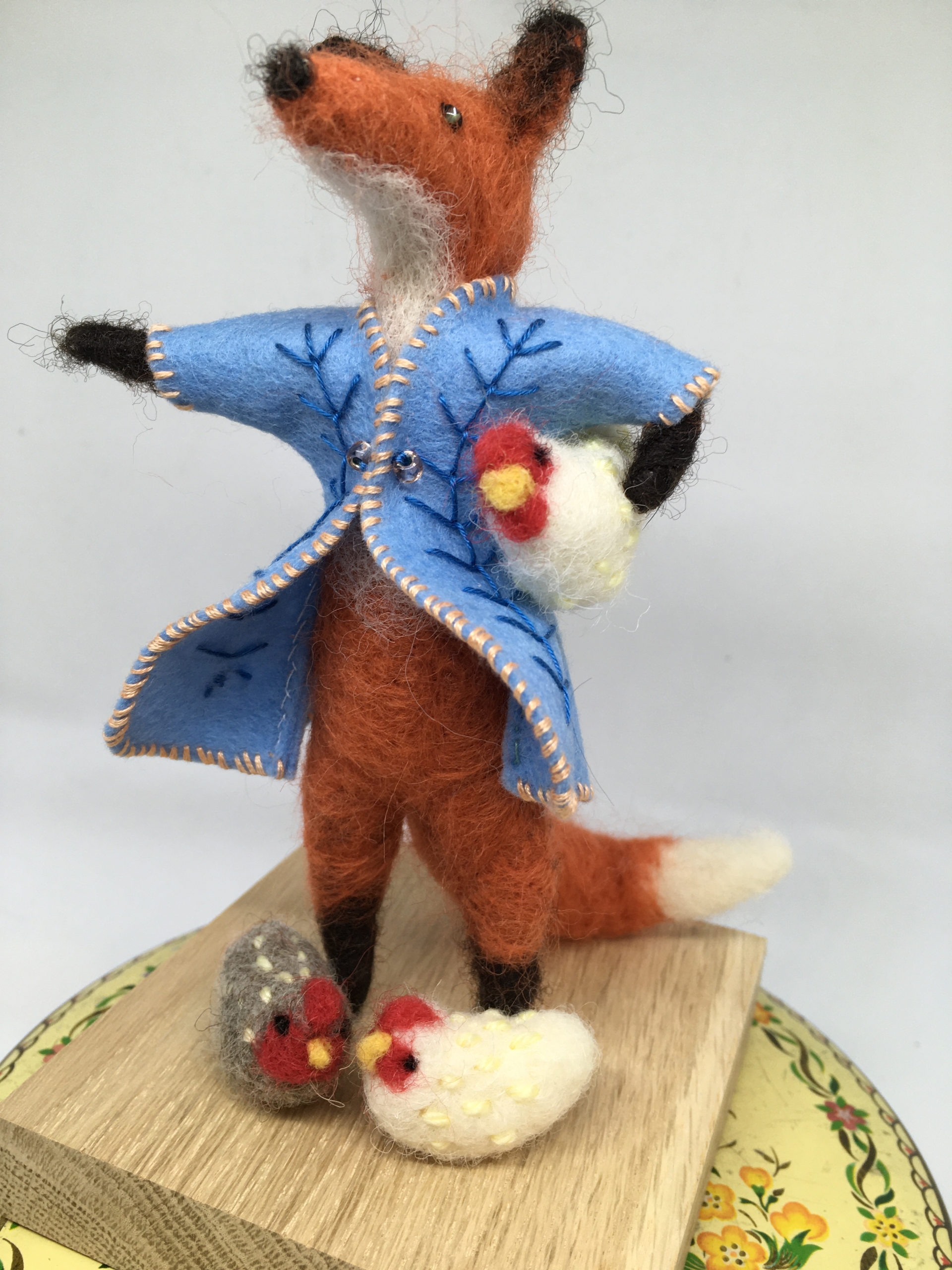 Felt fox doll holding three chicks.