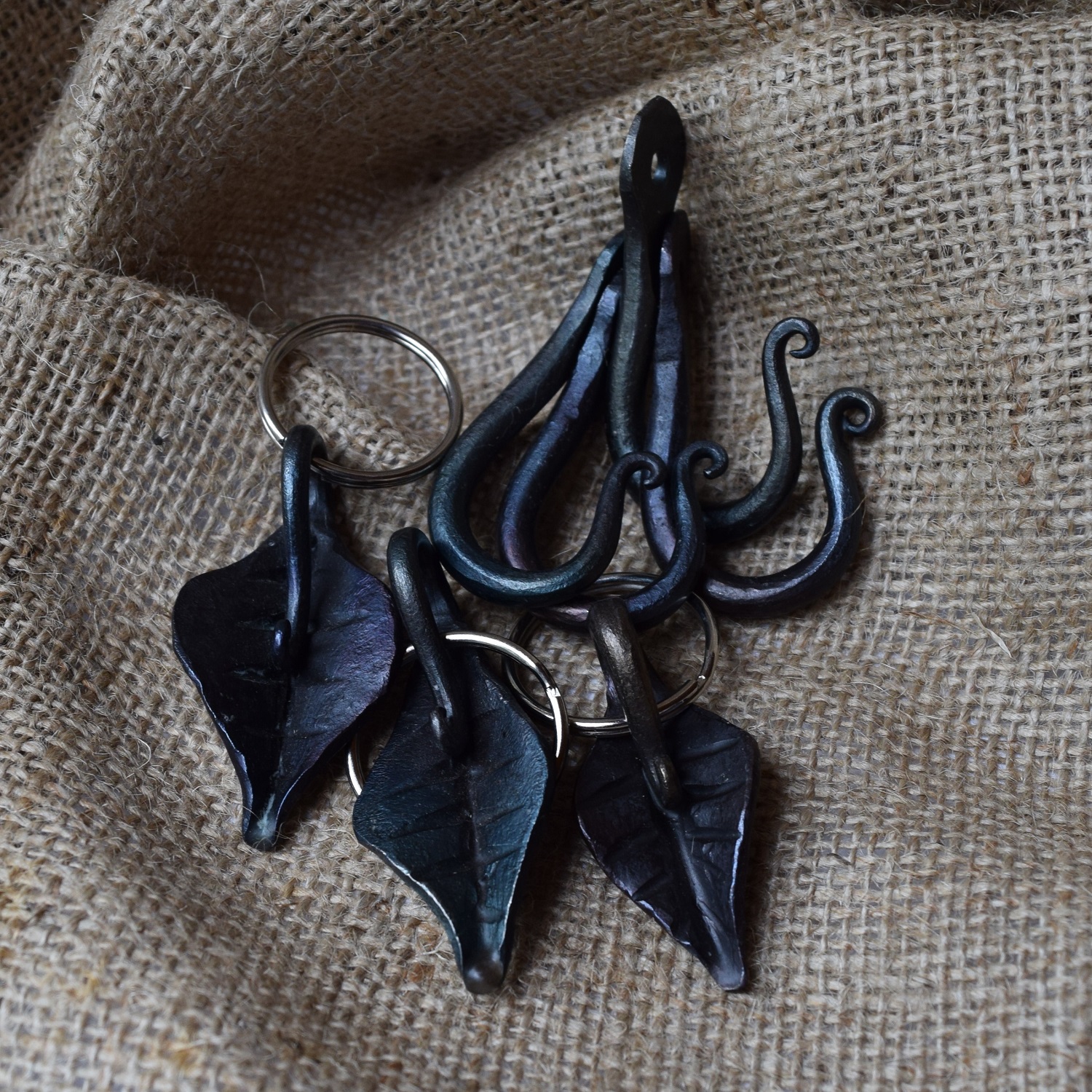 Black metal leaf keychains on burlap.