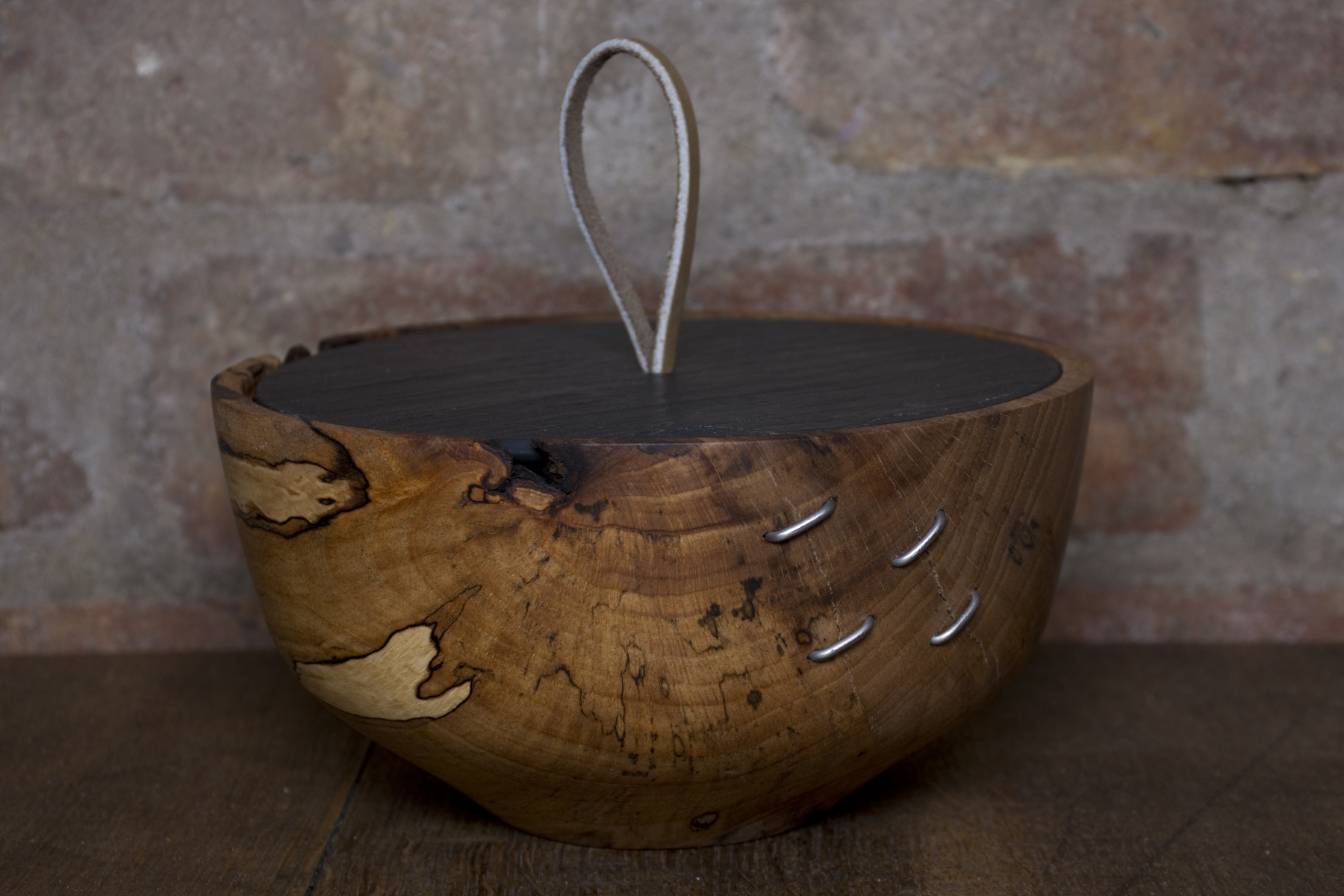 Wooden bowl with leather handle and rivets.