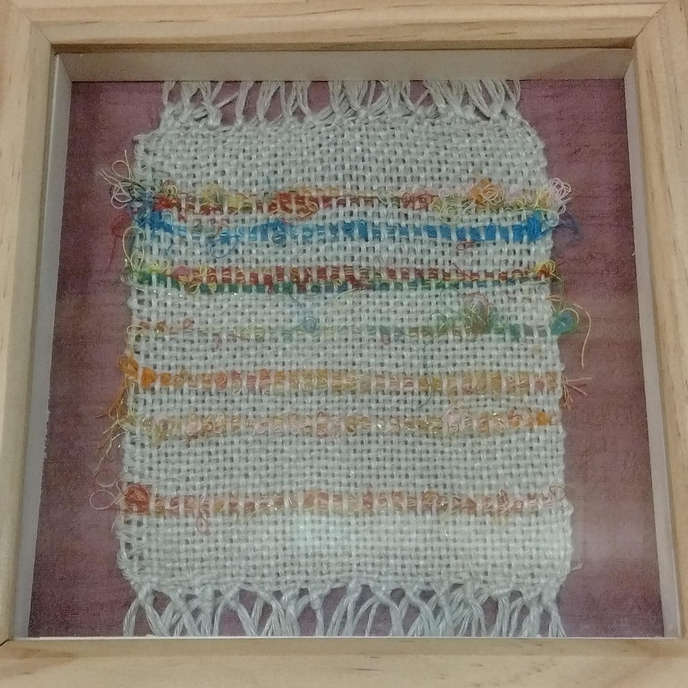 Framed woven fabric with colorful threads.